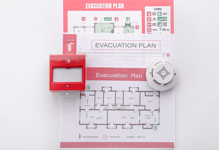 Evacuation plans, smoke detector and manual call point on white background