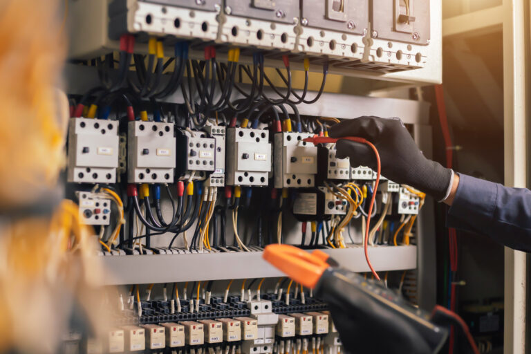 Electrician engineer work tester measuring voltage and current of power electric line in electical cabinet control.and wires on relay protection system. Bay control unit. Medium voltage switchgear.